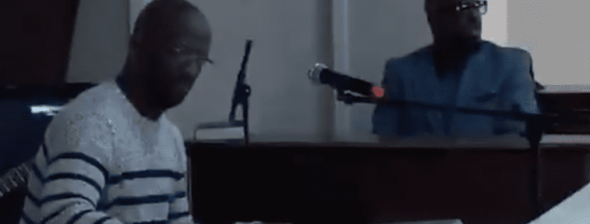 Two musicians performing with piano and microphone.